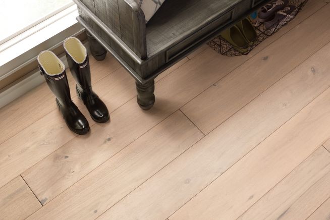 light toned hardwood flooring in an entryway with a bench and boots.